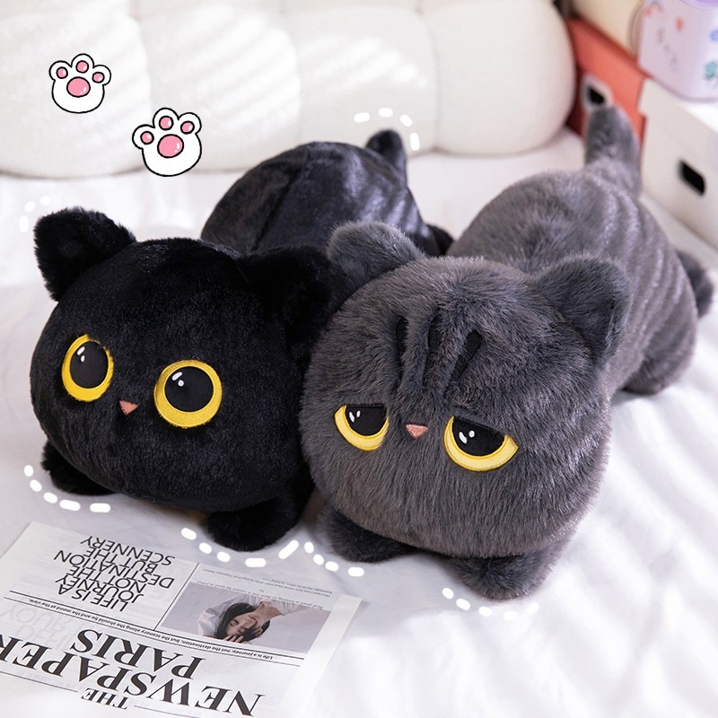 Black and gray lying cat plush pillows on a bed