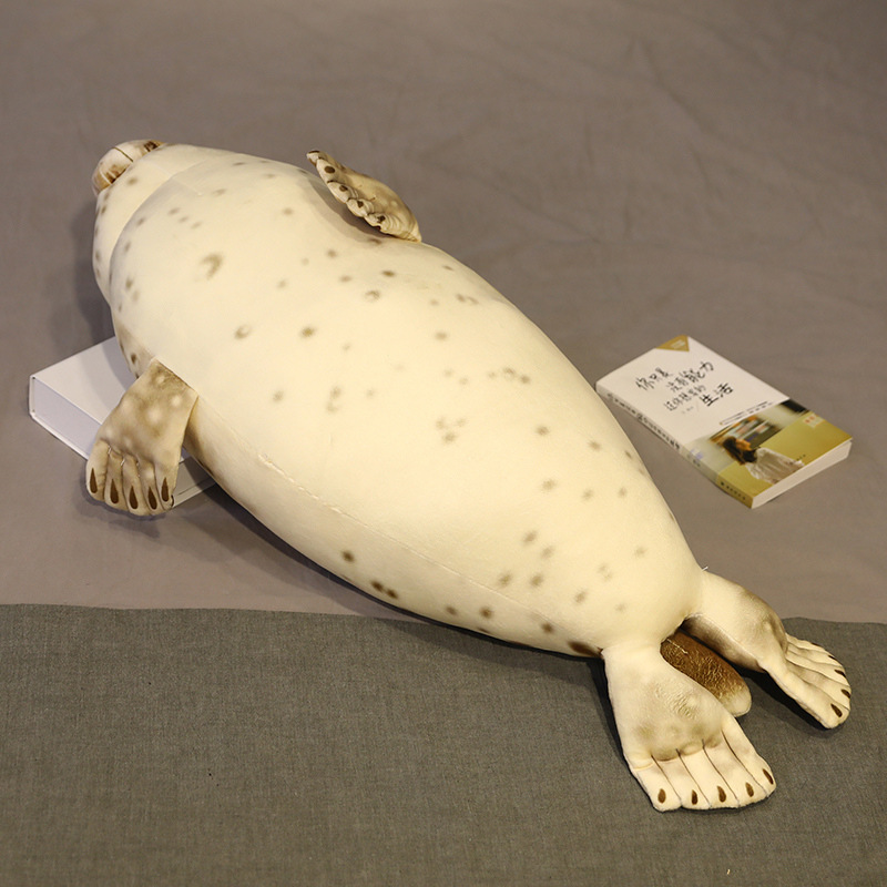 Seal plush pillow lying on bed showing full body length and smooth plush fabric