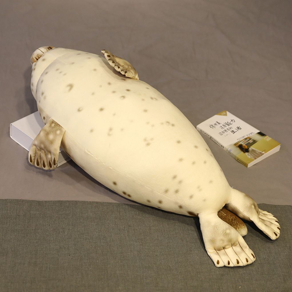 Seal plush pillow lying on bed showing full body length and smooth plush fabric