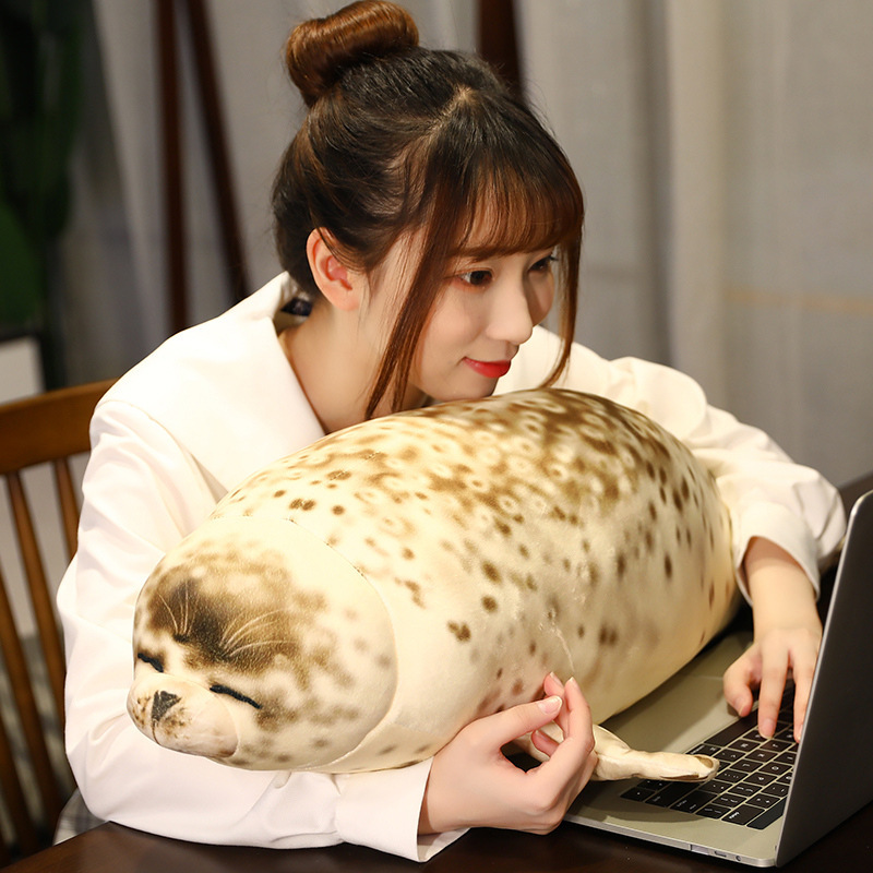 Seal plush pillow used for arm support while working on a laptop at a desk