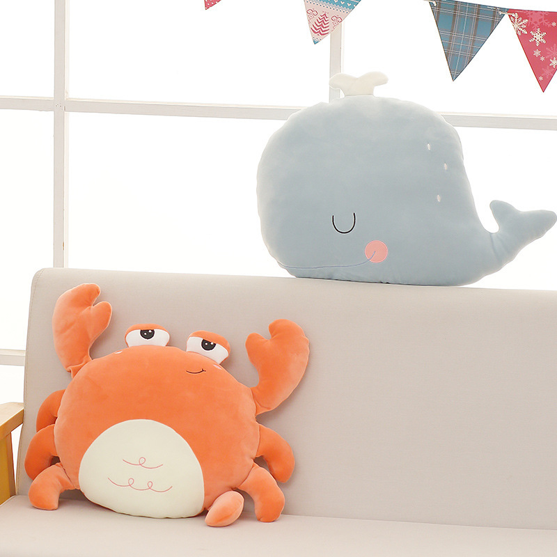 Adorable crab and whale plush pillows on a sofa in a cozy home setting
