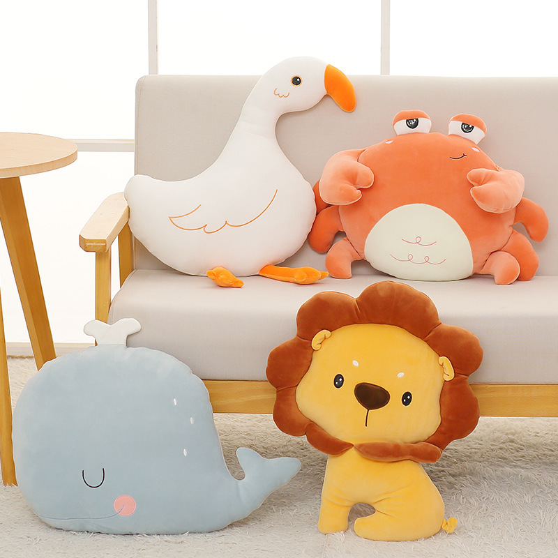 Cute crab, whale, goose, and lion plush pillows displayed on a sofa in a cozy living room