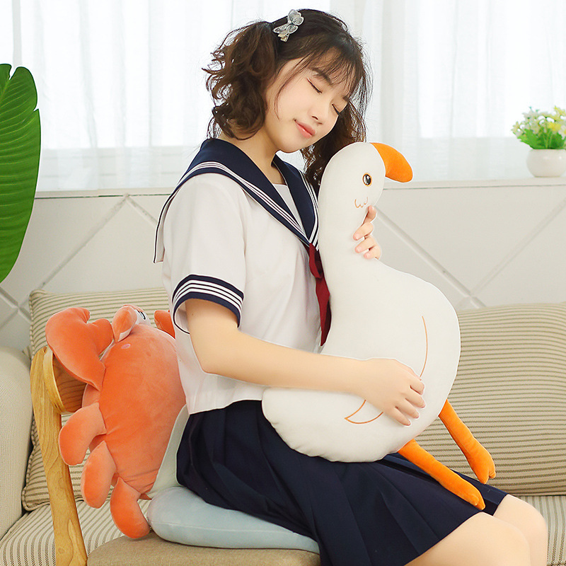 Goose plush pillow being hugged for comfort, with whale and crab plush cushions creating a cozy and relaxing home setting