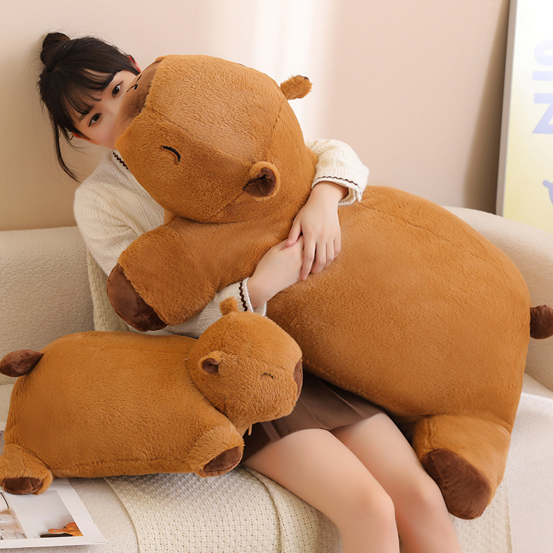 Capybara plush cushion in large and small sizes placed on a sofa, showing its soft texture and huggable design for relaxing and lounging