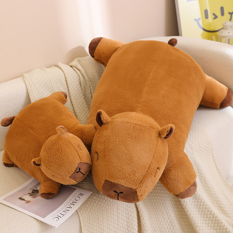 Capybara plush cushion in large and small sizes resting on a sofa, soft and huggable design for relaxing, lounging, or cozy home decor