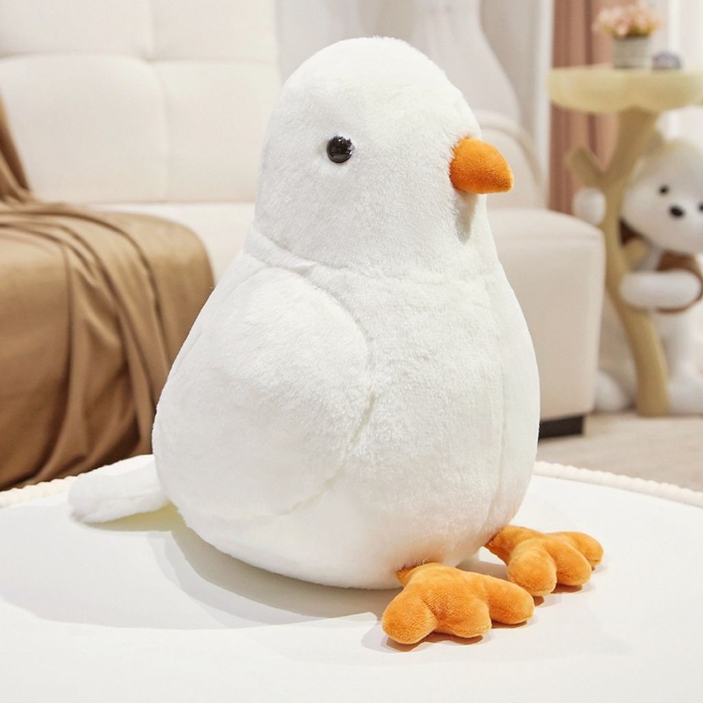 White pigeon plush toy with soft rounded body and orange beak on cozy sofa