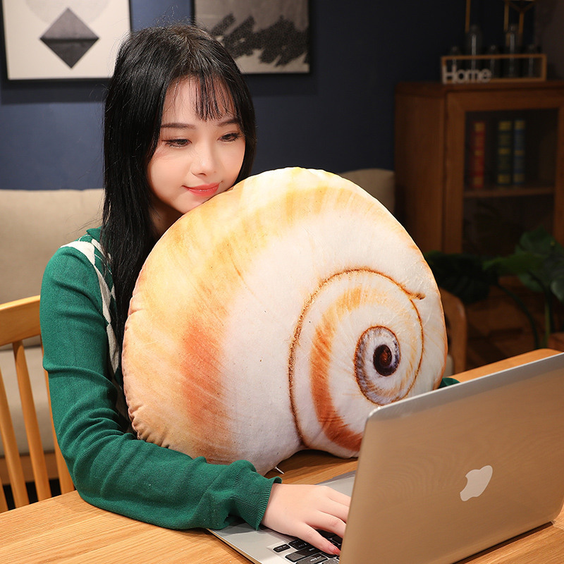 Realistic conch shell plush pillow used as a soft support cushion while working at a desk, adding a cozy and ocean-inspired touch to the workspace
