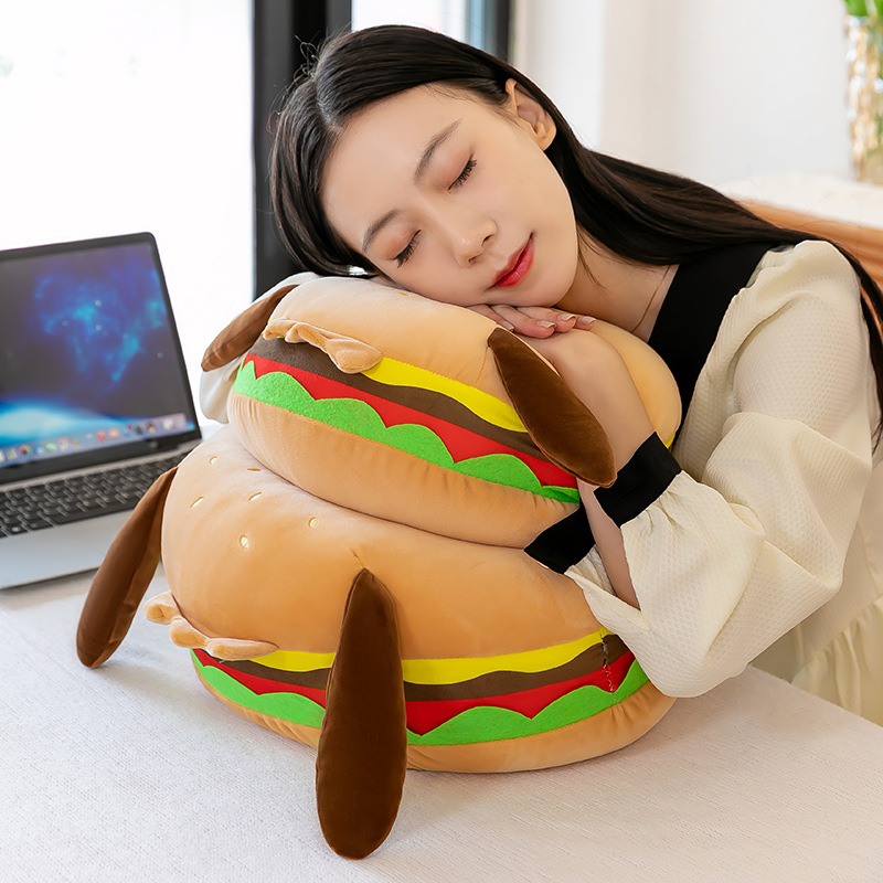 Burger dog plush pillow used as a soft hugging pillow for desk naps and relaxation in a cozy home setting