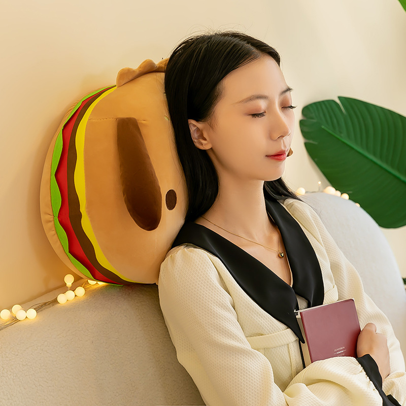 Burger dog plush pillow used as a soft back and neck support on a sofa, cozy plush cushion for relaxing, reading, or resting at home