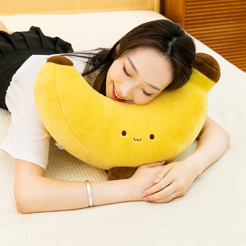 Banana plush toy with legs used as a soft cuddle pillow on bed, cozy home setting for relaxing and resting