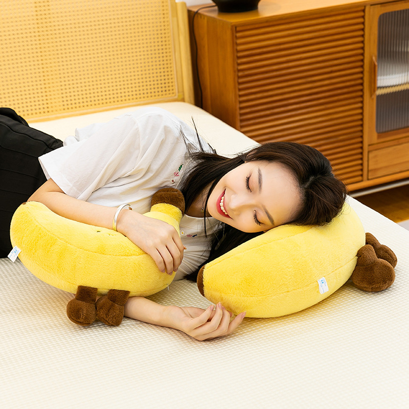 Banana plush toy with legs used as a soft sleeping pillow on bed, cozy bedroom scene for relaxation and comfort