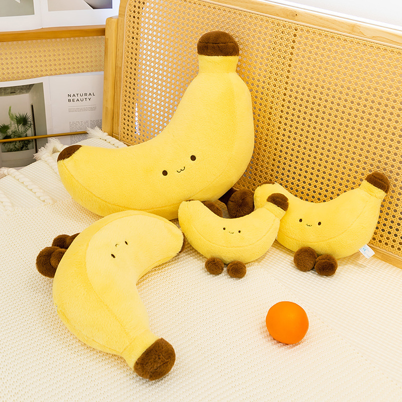 Banana plush toy with legs in different sizes arranged on a bed, soft banana plush used as decorative cushions for bedroom styling, cozy and cheerful home decor vibe