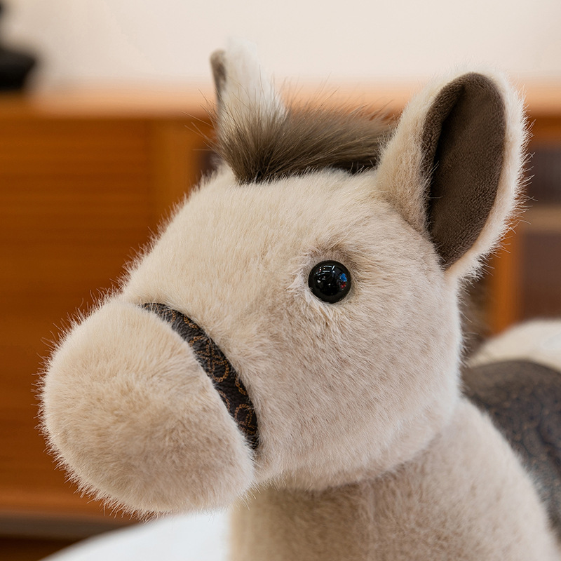 Realistic pony plush toy close-up showing soft muzzle texture and gentle facial details in a cozy indoor setting