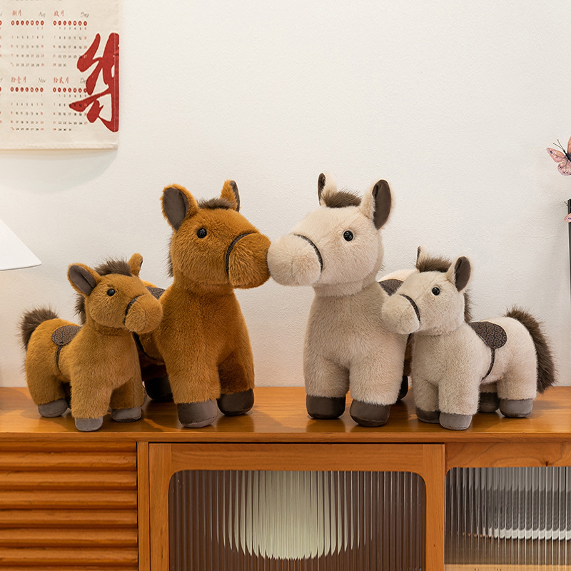 Realistic pony plush toys in multiple sizes and colors displayed together on a wooden cabinet showing soft texture saddle detail and warm decorative style for home and gift use