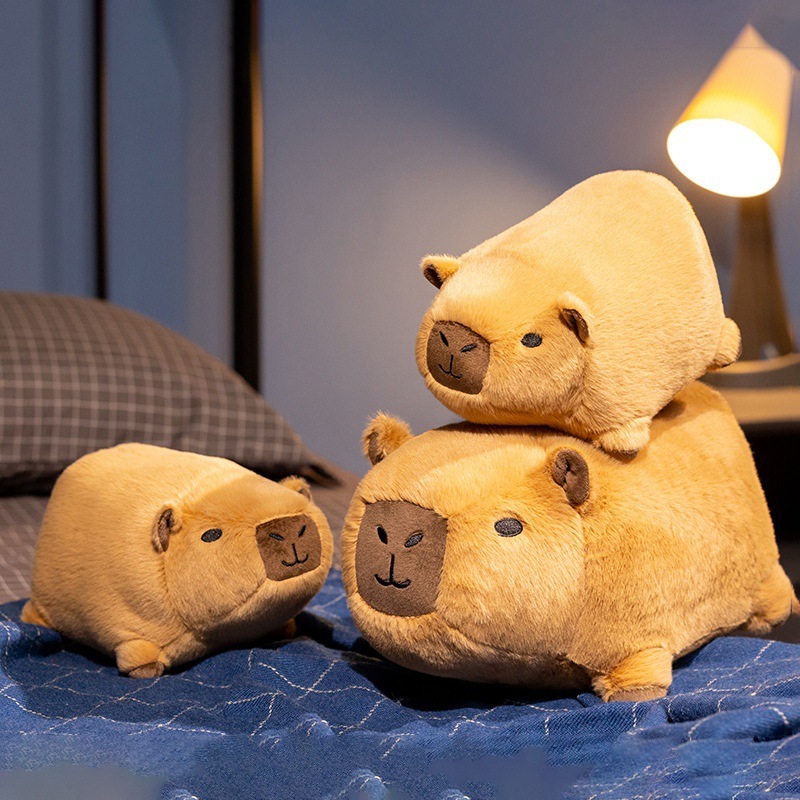 Capybara plush toy size comparison on bed showing 24 cm and 35 cm stuffed animals