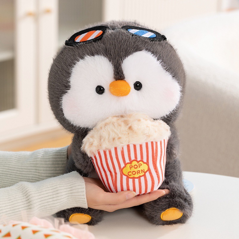 Coco penguin plush toy holding a popcorn snack, soft fluffy texture with round shape, designed for cozy hugging and home decor, creating a warm and playful movie night atmosphere