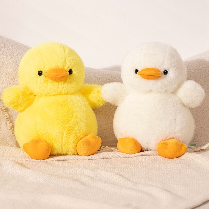 Two duck plush toys in yellow and white placed side by side, featuring a soft fluffy texture and a cozy, relaxing home decor setting