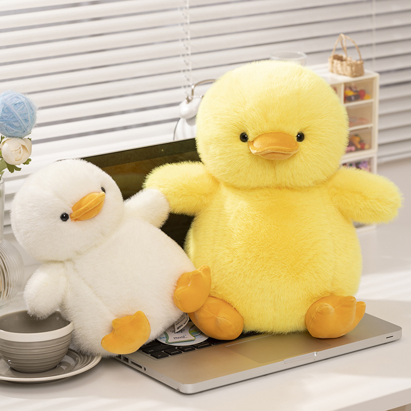 Duck plush toys in yellow and white displayed on a desk, highlighting different sizes with a soft plush texture and cozy everyday setting