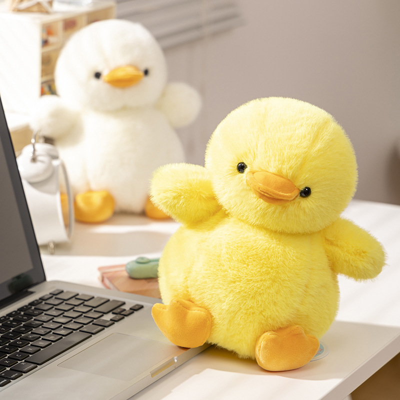 Yellow duck plush toy sitting on a desk with a soft rounded shape, used as a comforting decor piece for home or workspace, creating a warm, playful, and relaxing atmosphere