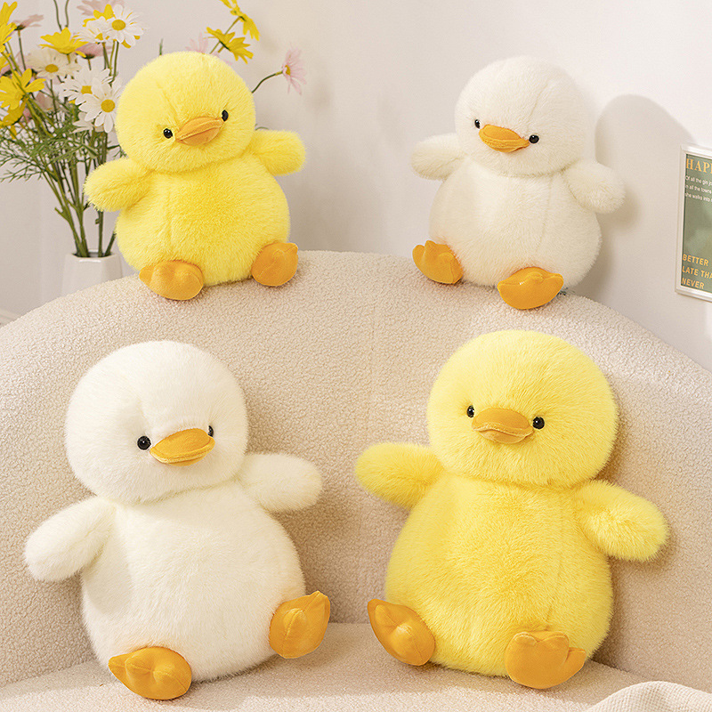 Duck plush toys displayed in a cozy living space, showing yellow and white color options with a soft plush texture and decorative styling