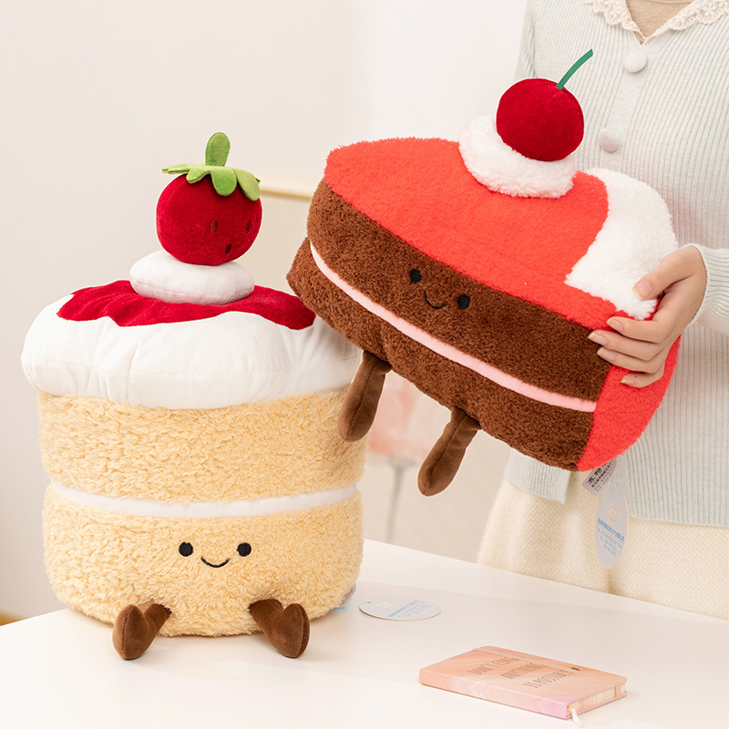 Dessert cake plush toys in strawberry velvet and triangle mousse designs, shown on a table with soft textures for cozy hugging and home decor