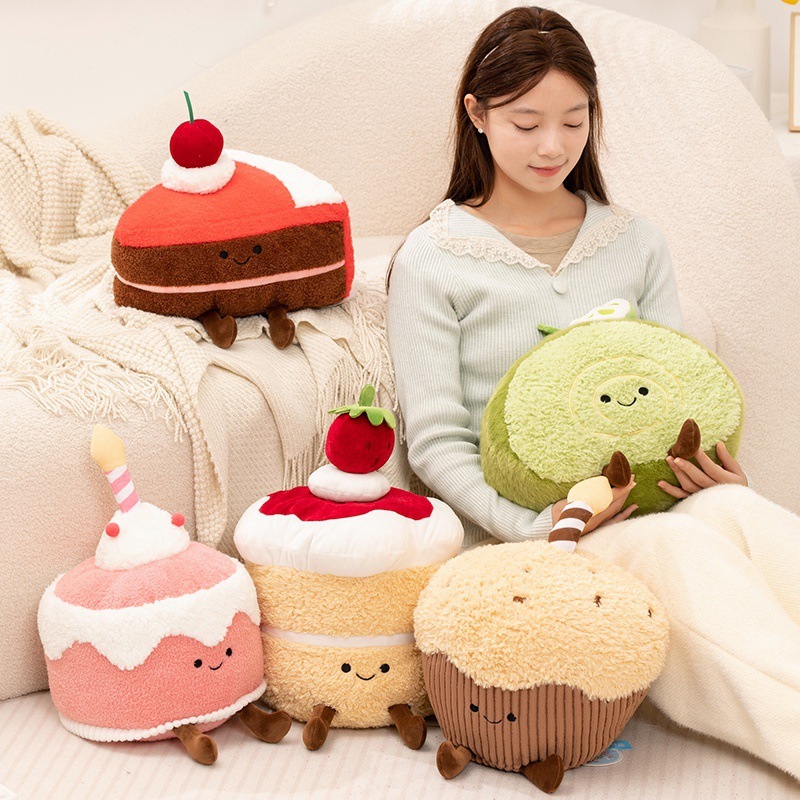 Dessert cake plush toy collection displayed on a sofa, featuring Swiss roll, mousse, muffin, and cake designs, creating a soft, cozy, and playful dessert-themed home decor setting