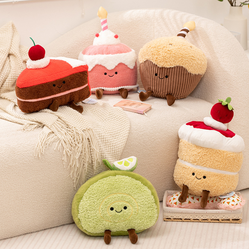 Dessert cake plush toy collection displayed on a sofa, including Swiss roll, mousse, muffin, and cake designs, creating a cute and cozy dessert-themed home decor scene