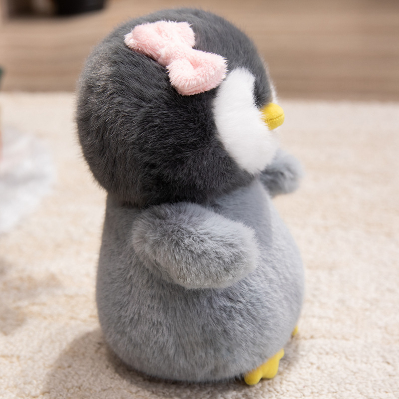 Side view of a bow penguin plush toy with fluffy gray plush texture, rounded shape, small wings, and pink bow accent, highlighting its soft and huggable design