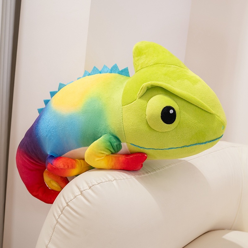 Colorful chameleon plush toy resting on a sofa arm, showing rainbow gradient fabric and soft huggable shape for cozy home decor