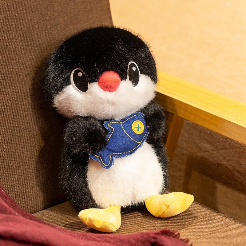Penguin plush toy holding a fish, displayed on a chair as a cozy home decor plush companion