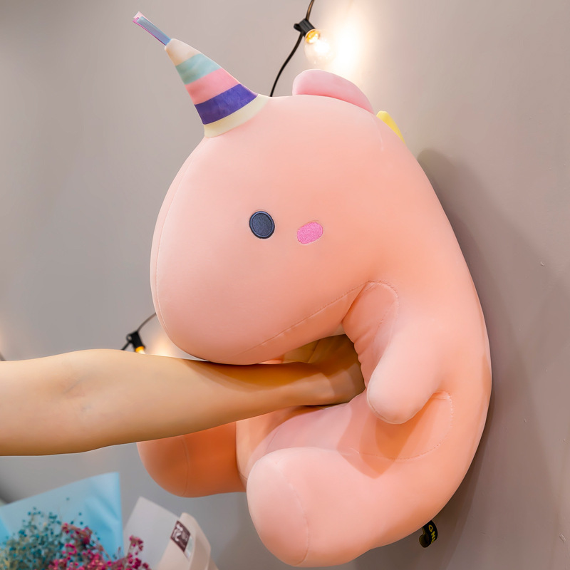 Candy dinosaur plush toy in soft pink color pressed gently against a wall, highlighting its soft plush texture, squishy feel, and flexible shape for comfort and stress relief