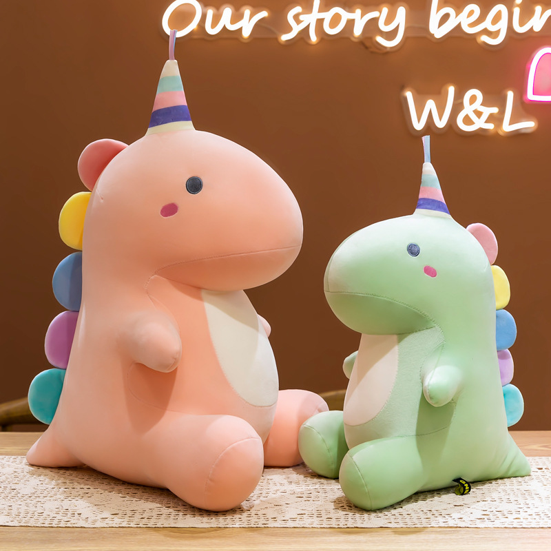 Candy dinosaur plush toys in pastel pink and green colors displayed together on a table, featuring a cute sitting design that adds a playful and cozy atmosphere to home decor