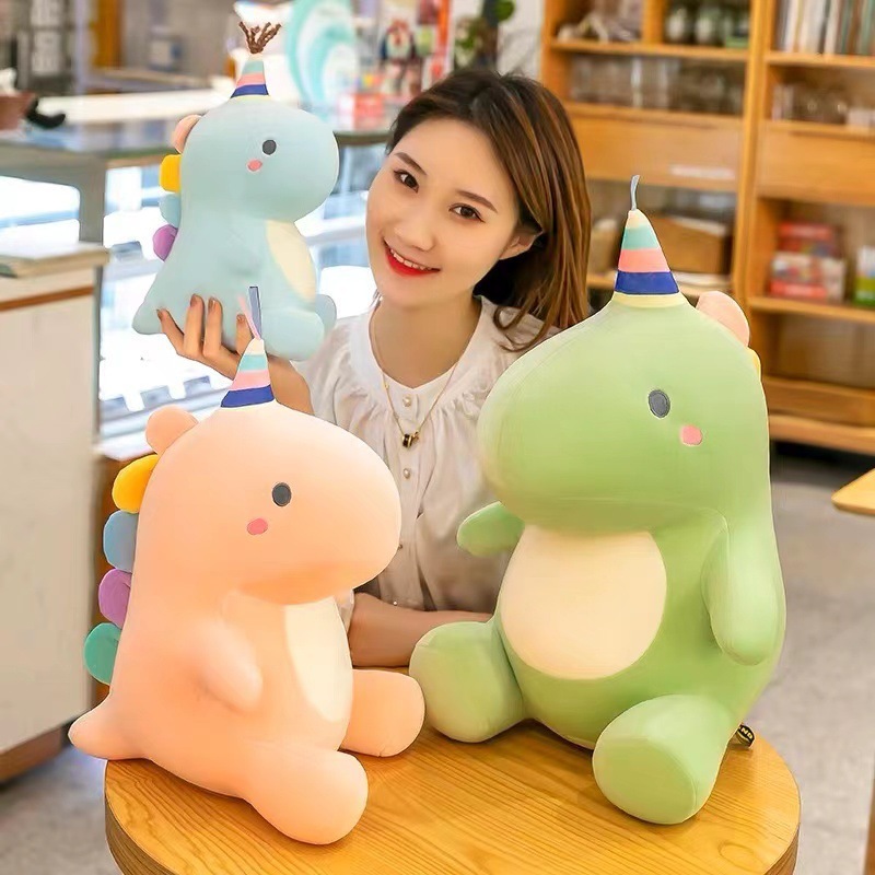 Candy dinosaur plush toys in multiple sizes placed on a table in a warm indoor setting, showing soft texture, pastel colors, and a comfortable huggable design ideal for gifts and home decor