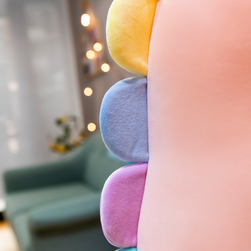 Candy dinosaur plush toy back detail featuring colorful padded spikes, soft plush texture, and gentle pastel tones, styled in a warm and cozy home environment