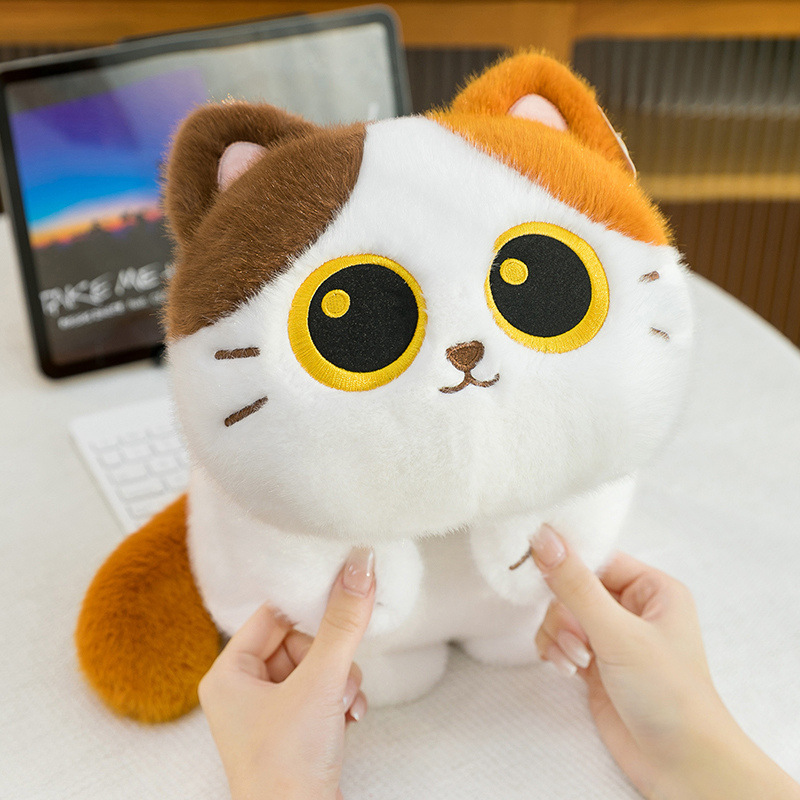 Soft lying calico cat plush toy gently squeezed showing fluffy texture and rounded shape for cozy comfort