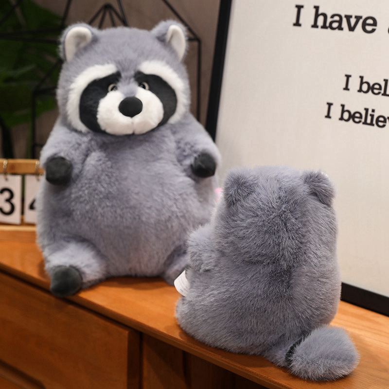 Chubby raccoon plush toy showing soft plush texture and rounded shape, displayed from front and back on a wooden shelf, highlighting cozy design and cuddly feel for home decor