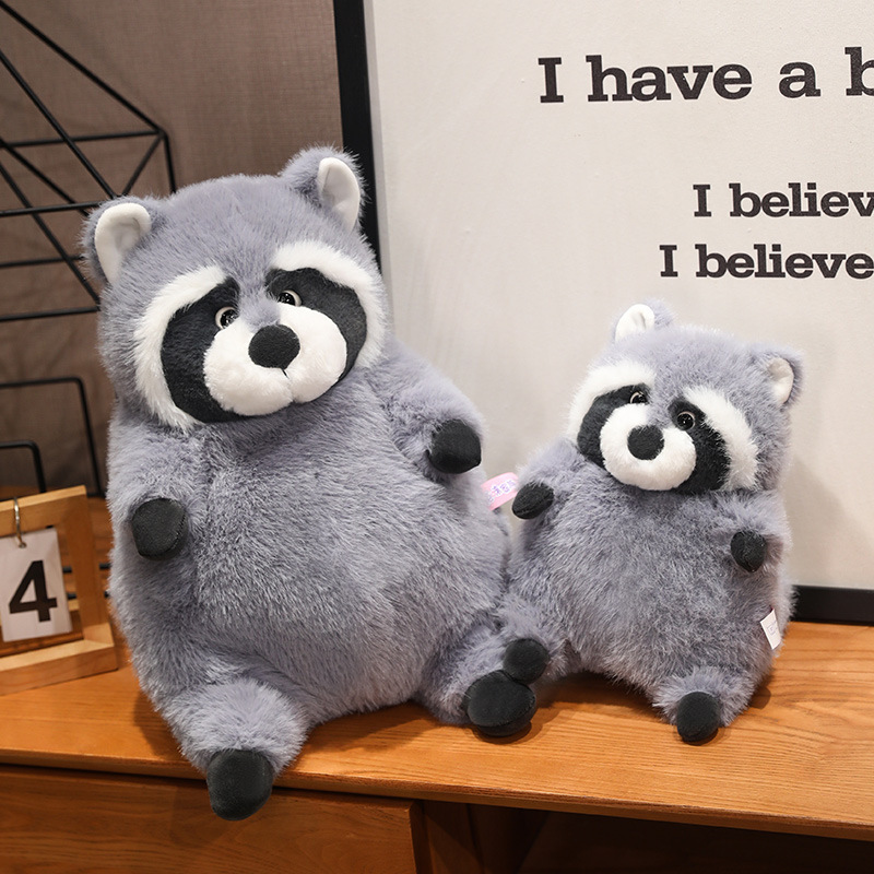 Chubby raccoon plush toys in two sizes placed side by side on a shelf, featuring fluffy plush fabric and adorable sitting design, ideal for hugging or decorating cozy living spaces