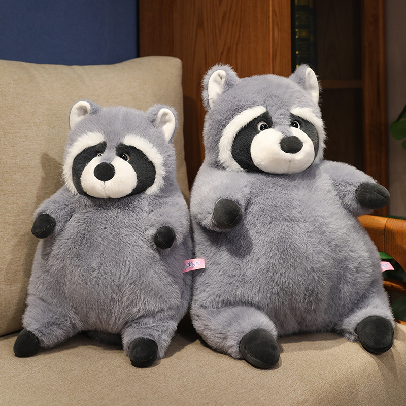 Two chubby raccoon plush toys sitting side by side on a sofa, showing different sizes with fluffy texture and rounded shape, ideal for sofa decoration, cuddling, and adding a cozy touch to living spaces