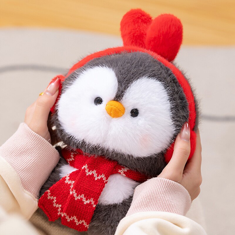 Coco standing penguin plush toy with red ear muffs and scarf, soft fluffy texture shown up close, designed for cozy hugging and comforting home moments