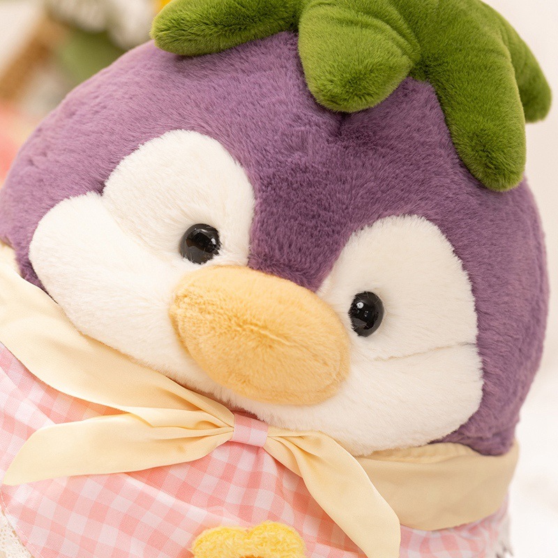 Eggplant penguin plush toy close-up showing soft plush fabric, embroidered eyes, and spring outfit scarf details