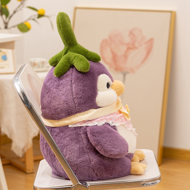 Side view of eggplant penguin plush toy on a chair, rounded shape with soft plush texture, decorative stuffed animal for cozy indoor spaces