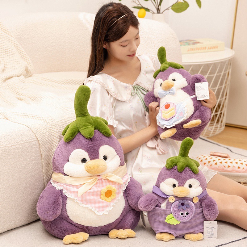 Eggplant penguin plush toy displayed on a sofa in a cozy home setting, soft and huggable stuffed animal ideal for relaxing, cuddling, and decorating living rooms or bedrooms