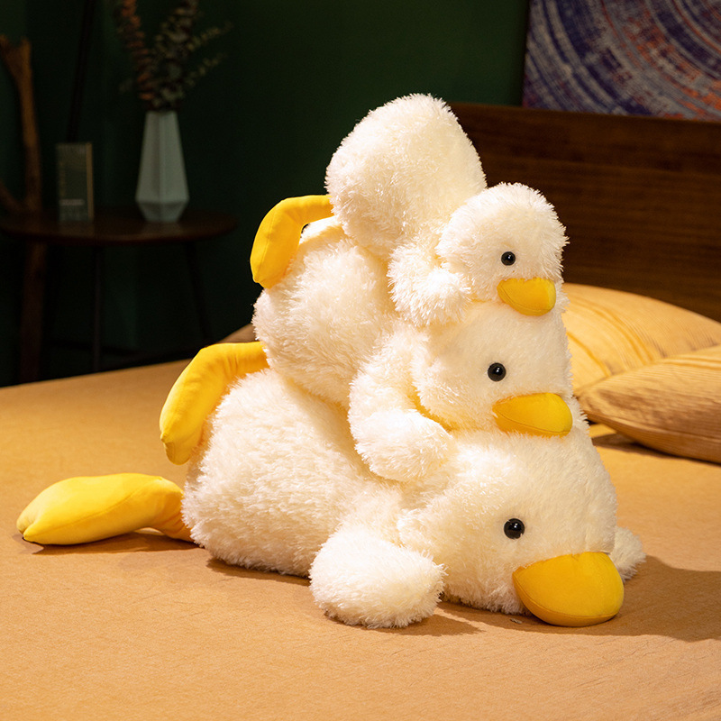 Lying white duck plush pillows stacked together on a bed, highlighting their soft plush material, rounded design, and cozy bedroom atmosphere