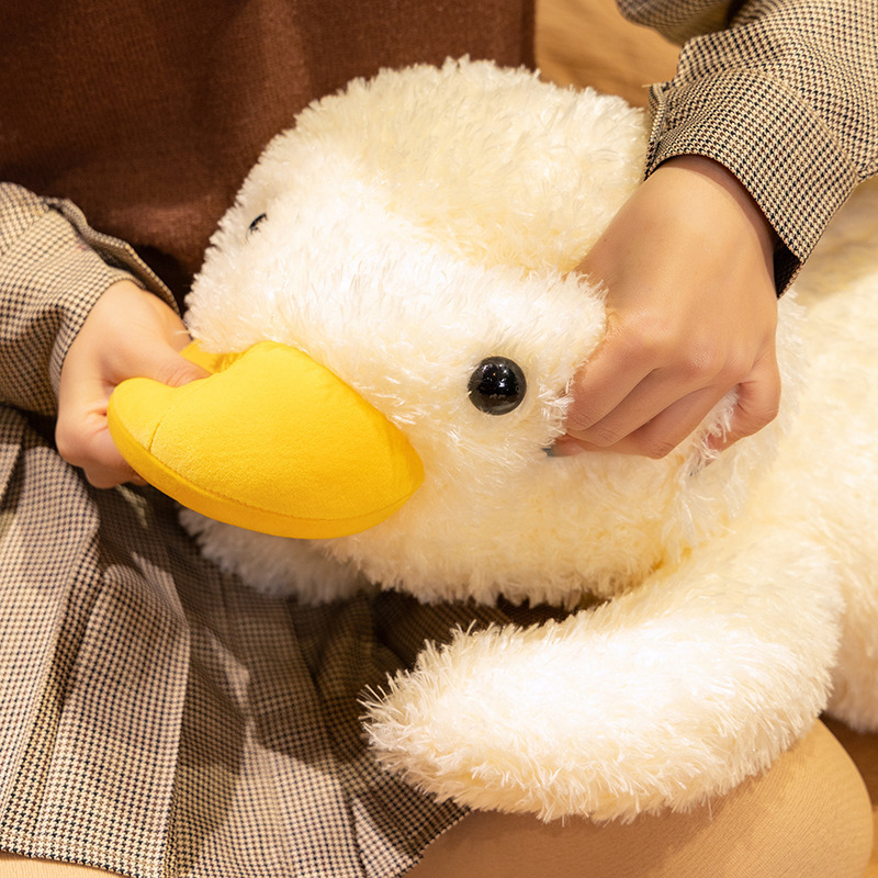 Lying white duck plush pillow being gently squeezed to show its soft, fluffy texture and comfortable cushioning