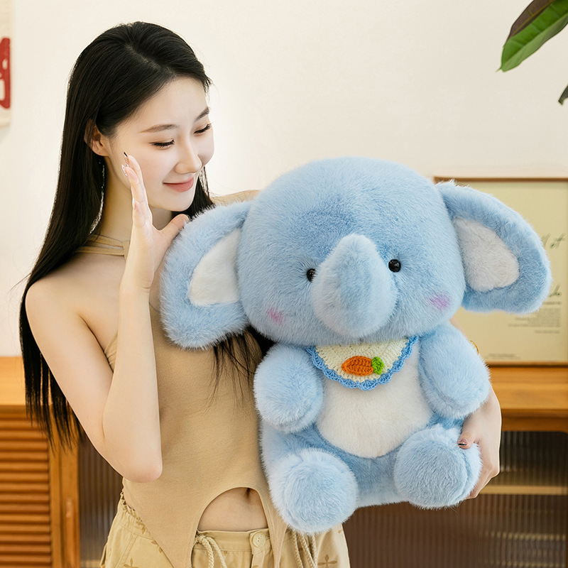Happy elephant plush toy held close, showing soft blue plush fabric, rounded ears, embroidered bib detail, and a cuddly size ideal for hugging, comfort, and cozy home decor