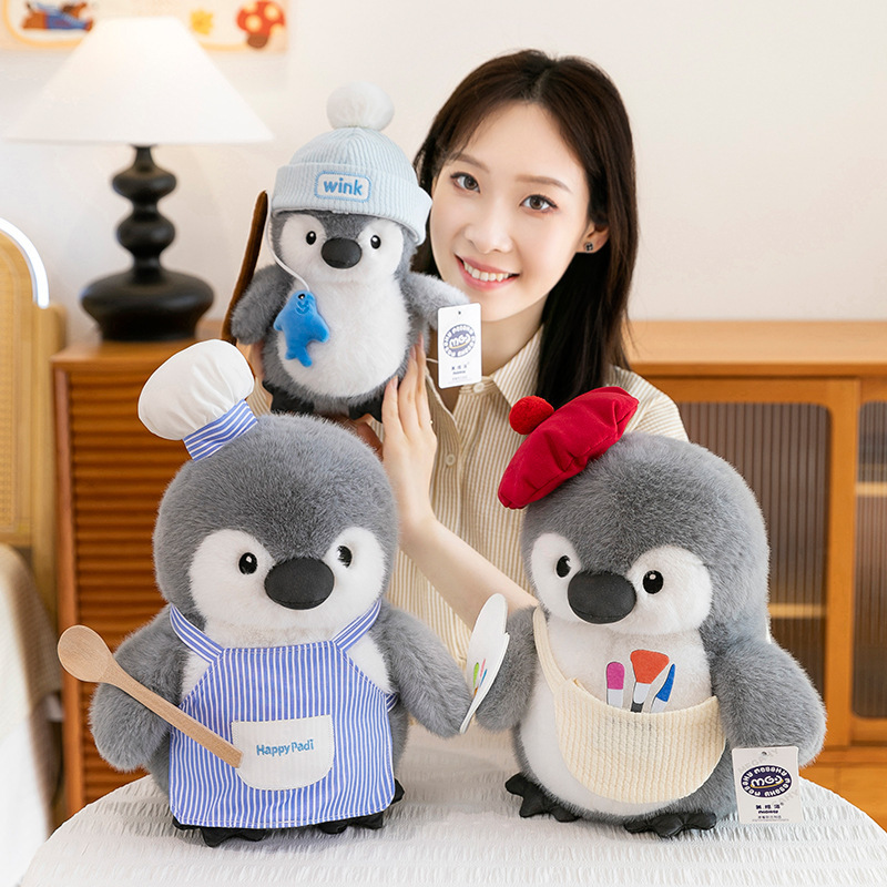 Chubby penguin plush toys in chef, painter and fishing designs displayed on a table, showcasing soft texture, cozy feel and playful home decor atmosphere