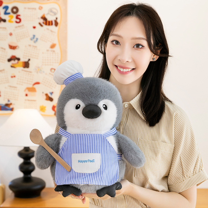 Chef penguin plush toy with striped apron and wooden spoon detail, soft and huggable plush texture, perfect for cozy home decor, hugging, or display