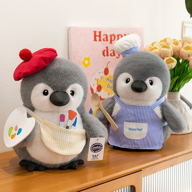 Chef and painter chubby penguin plush toys displayed on a cabinet, showcasing cute themed outfits, soft plush fabric and warm home decor atmosphere