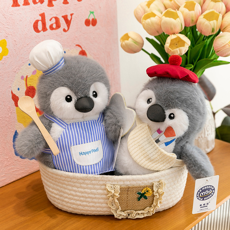 Chef and painter penguin plush toys placed in a woven basket, showing cute details, soft fabric, and cozy decorative use in a warm home setting