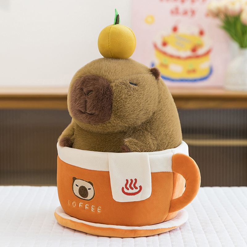 Coffee cup capybara plush toy sitting inside orange coffee cup with saucer on table